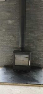 Mi Fires Solway stove with black TW Pro flue against stone wall backdrop in Bwlchnewydd, Carmarthenshire - installed by Hopkins Log Burners