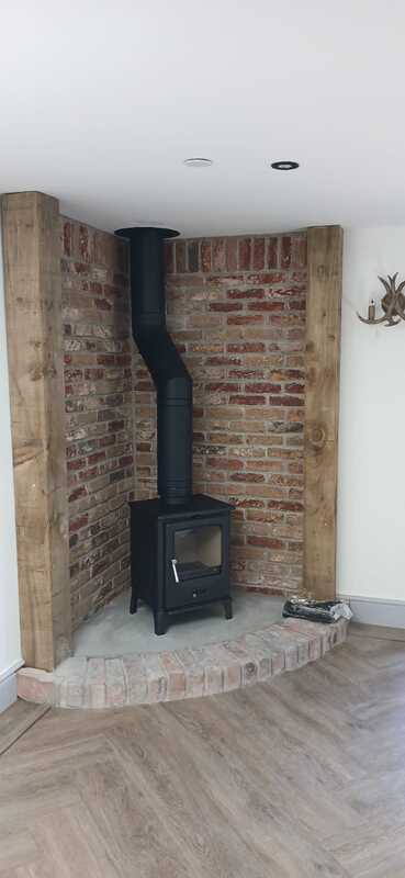 Side view of F2 Accona Slider multifuel stove with angled flue installation in converted milking shed by Hopkins Log Burners in Bynea, Llanelli
