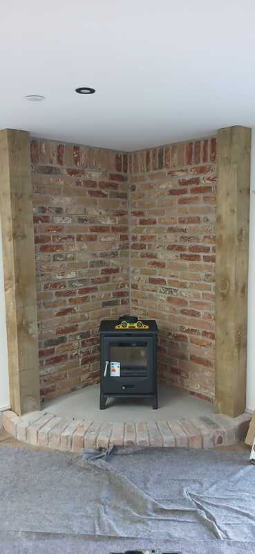 F2 Accona Slider wood burning stove positioned in corner brick alcove during installation by Hopkins Log Burners in Bynea, Llanelli