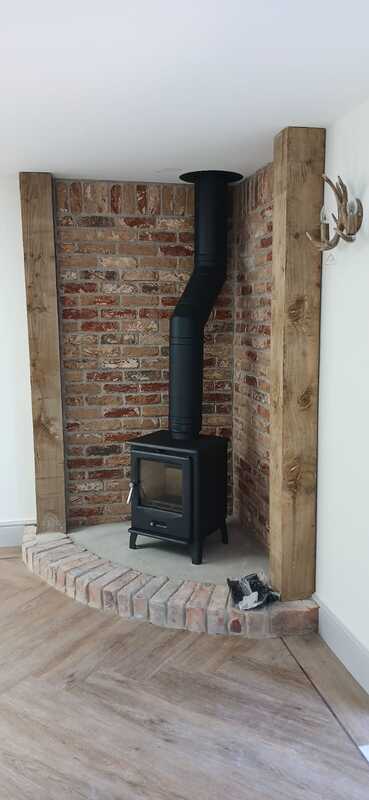 F2 Accona Slider multifuel stove with angled flue pipe installation in rustic brick corner with decorative antler feature by Hopkins Log Burners in Bynea, Llanelli