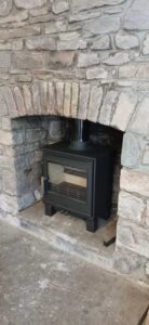 Completed ACR Malvern stove installation with vitreous flue pipe in farmhouse stone hearth Llanddeusant