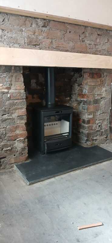 Professional Fireline FQ5W multifuel stove installation by Hopkins Log Burners showing completed project in Pwll Llanelli with vitreous flue pipe and cast iron door